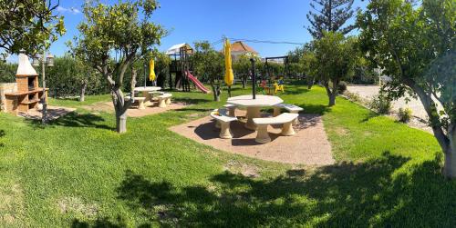 un parc avec plusieurs tables de pique-nique et une aire de jeux dans l'établissement Casa da Horta, Vale carro Olhos de Agua, à Albufeira