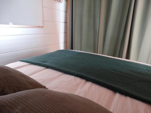 Una cama con una manta verde encima. en les Lodges de la tortue permacole Douce verveine, en Champclause
