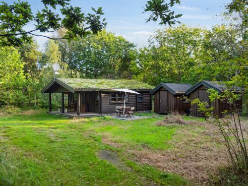 eine Hütte im Wald mit einem Rasenplatz in der Unterkunft Holiday Home Tumi - 700m from the sea in NE Jutland by Interhome in Læsø