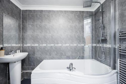 a bathroom with a bath tub and a sink at 2 Bedroom House by AV Stays Short Lets Croydon With Free Wi-Fi in South Norwood