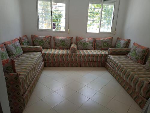 ein Wohnzimmer mit einem Sofa und 2 Fenstern in der Unterkunft très joli appartement près de la mer in Kenitra