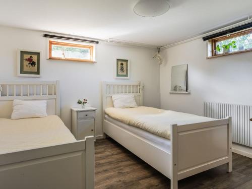 two beds in a bedroom with white walls and wooden floors at Holiday Home Ryedal by Interhome in Svängsta