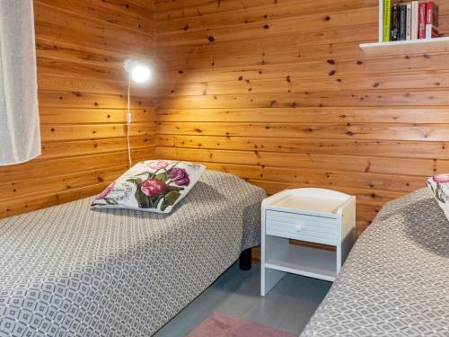 two beds in a room with a wooden wall at Holiday Home Mäkitupa by Interhome in Syöte