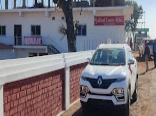 a white car parked next to a brick wall at Hotel Center Point Kamleshwarpur 