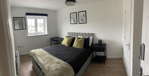 a bedroom with a bed with two tables and a window at Supreme Apartments in Keighley