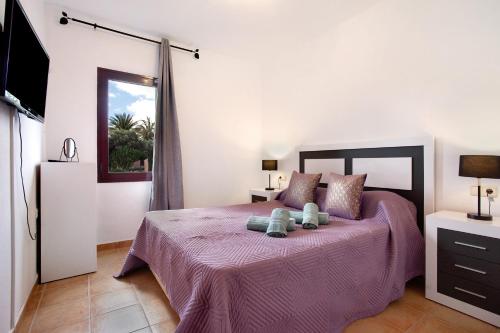 Un dormitorio con una cama morada con dos ositos de peluche. en Villa Malva en Corralejo