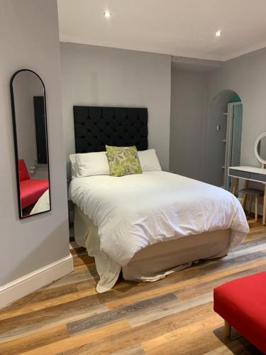 a bedroom with a bed with a mirror and a red chair at Entire apartment in central Brighton in Brighton & Hove