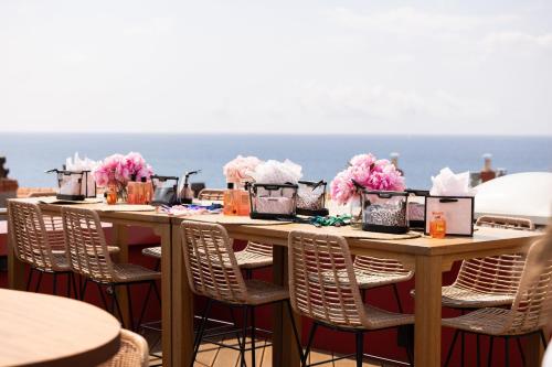 a long table with chairs and pink flowers on it at AC Hotel by Marriott Nice in Nice