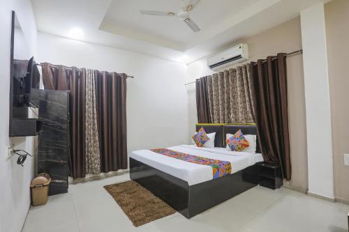 a bedroom with a bed in a room with curtains at FabHotel Paradise Stay Inn in Nagpur