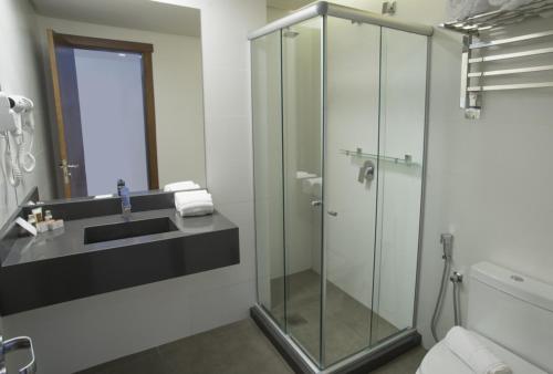 a bathroom with a glass shower and a sink at Hotel Laghetto Stilo Centro in Gramado