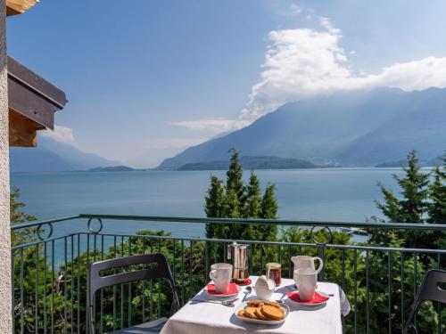 a table with food on a balcony with a view of a lake at Apartment Serenella by Interhome in Gravedona