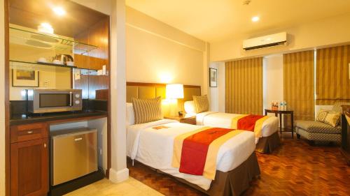 a hotel room with two beds and a television at RedDoorz Premium at The Residences Olympia Makati in Manila