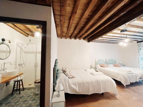 two beds in a room with a bathroom and a sink at Casa Rural Villa Margarita in Dosbarrios