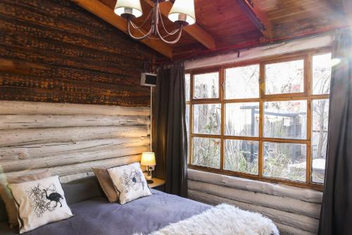 a bedroom with a wooden wall with a bed and a window at La Justina Hostel in San Carlos de Bariloche