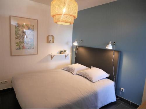 - une chambre avec un lit blanc et un mur bleu dans l'établissement Vieux-Lille - Studio en hypercentre, à Lille