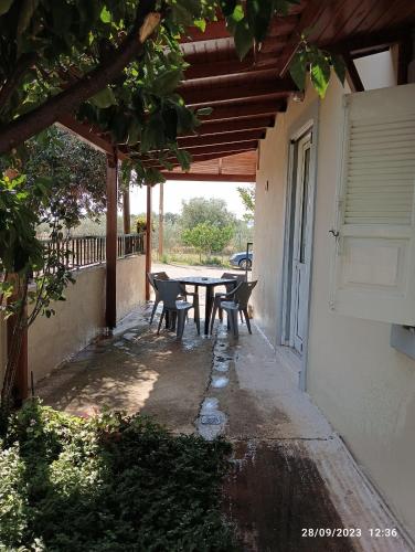 patio con tavolo e sedie sotto il portico di RENA APARTMENTS a Magoúla