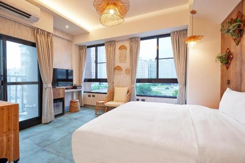 a bedroom with a large white bed and a tv at 星澄風旅 Zela Design Hotel in Kaohsiung