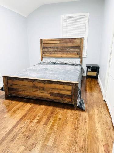 Łóżko w pokoju z drewnianą podłogą w obiekcie Cheerful 4-bedroom home with free parking w mieście Elmont