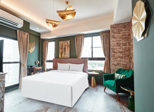 a bedroom with a white bed and a green chair at 星澄風旅 Zela Design Hotel in Kaohsiung
