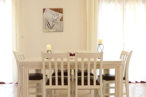 a dining room table with white chairs and a table and a painting at Villa Katia in Tsoukaladhes