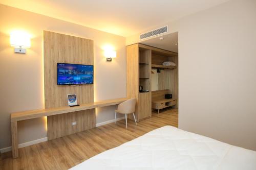a room with a bed and a desk with a tv at Regina Blu in Vlorë