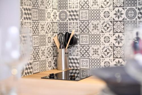 une tasse d'ustensiles sur un comptoir recouvert de carrelage dans l'établissement Studio MAGDA - Fibre et Tv - Calme et confortable, à Saint-Quentin
