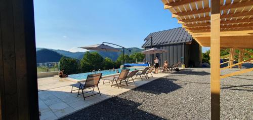 a pool with chairs and umbrellas next to a building at Cabanele CARMEL in Muntele Rece