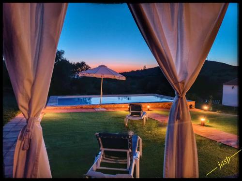 desde la ventana de un patio con sillas y sombrilla en Vivienda Rural Aroche Parralejo Chico, en Aroche