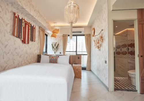 a bedroom with a white bed and a chandelier at 星澄風旅 Zela Design Hotel in Kaohsiung