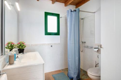 uma casa de banho com um chuveiro, um lavatório e um WC. em San roque em Tinajo