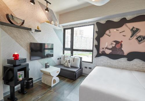 a bedroom with a bed and a tv and a couch at 星澄風旅 Zela Design Hotel in Kaohsiung