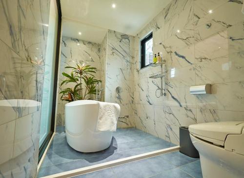 a bathroom with a tub and a toilet and a sink at 星澄風旅 Zela Design Hotel in Kaohsiung