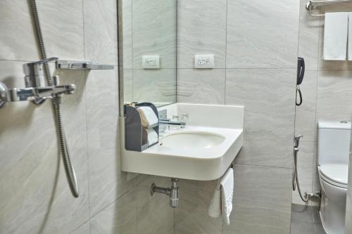 a bathroom with a sink and a toilet at Belmont Hotel Manila in Manila