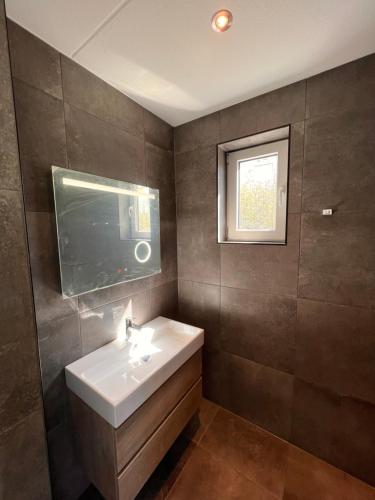 a bathroom with a white sink and a window at Luxe villa op Vakantiepark de Koorn-aar in Den Burg