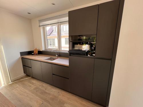 a kitchen with a sink and a microwave at Luxe villa op Vakantiepark de Koorn-aar in Den Burg