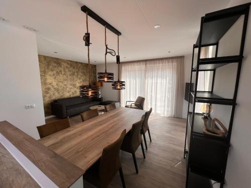 een eetkamer en een woonkamer met een grote houten tafel bij Luxe villa op Vakantiepark de Koorn-aar in Den Burg