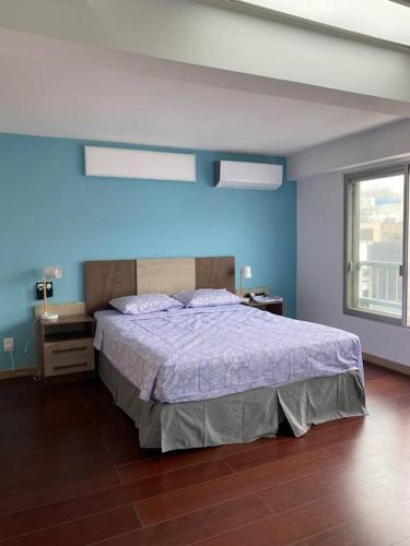 - une chambre avec un lit et un mur bleu dans l'établissement Apartamento en Barrio Sur DOS HABITACIONES, à Montevideo