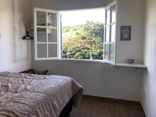 um quarto com uma cama e uma janela em Aconchegante Chalé - Recanto dos Canários 
