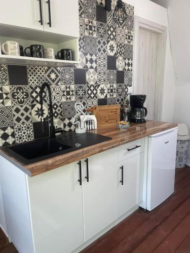 a kitchen with white cabinets and a black sink at Ellie's Eco Private Glamping and Spa in Nea Kalikratia