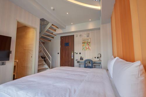a bedroom with a large white bed and a bathroom at 星澄風旅 Zela Design Hotel in Kaohsiung