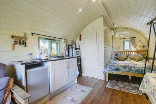 uma pequena cozinha numa pequena casa com uma cama em Pendragon Pod em Axminster