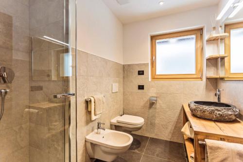 a bathroom with a toilet and a sink and a shower at Apartments Milanhof in Ortisei