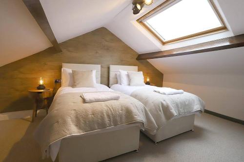 a attic bedroom with two beds and a skylight at Spinners Cottage - Central Kirkby Lonsdale Retreat in Kirkby Lonsdale