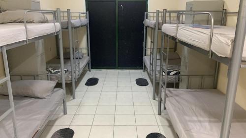a room with three bunk beds and a tiled floor at Rovers Boys Hostel Dubai Near Gold Souq Metro in Dubai