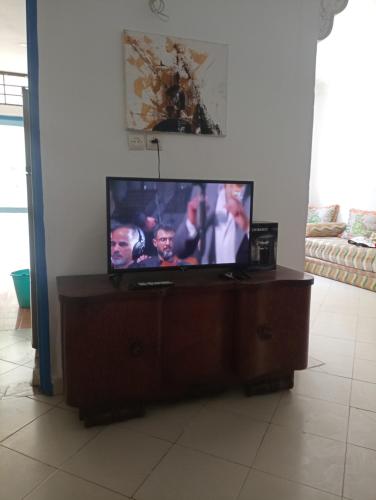 einen Flachbild-TV auf einem Stand in einem Wohnzimmer in der Unterkunft très joli appartement près de la mer in Kenitra