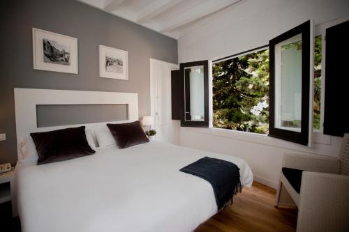 a bedroom with a white bed and two windows at Hotel Sitges Rooms in Sitges