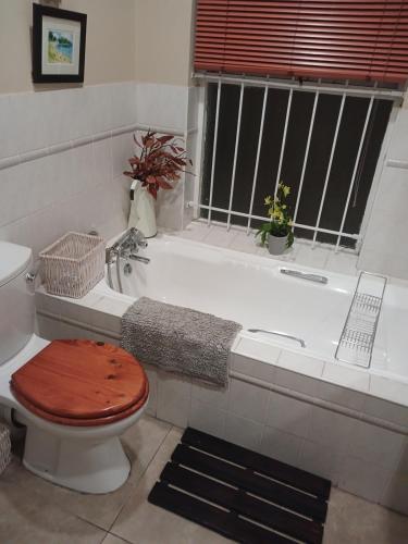 a bathroom with a toilet and a bath tub at Greenbank Cottage in Cape Town