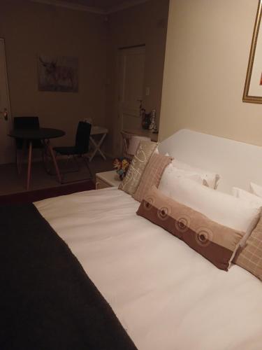 Cette chambre comprend un grand lit blanc et une table. dans l'établissement Greenbank Cottage, au Cap
