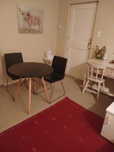 Una mesa y dos sillas en una habitación con puerta en Greenbank Cottage, en Ciudad del Cabo