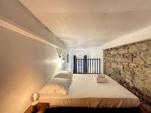 - un grand lit dans une chambre dotée d'un mur en pierre dans l'établissement Cosy Appt coeur de Lyon 1 Imbert, à Lyon